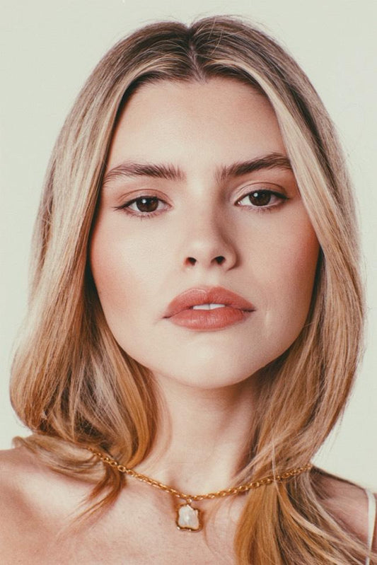 Long haired blonde model wearing necklace, photo taken front on to camera