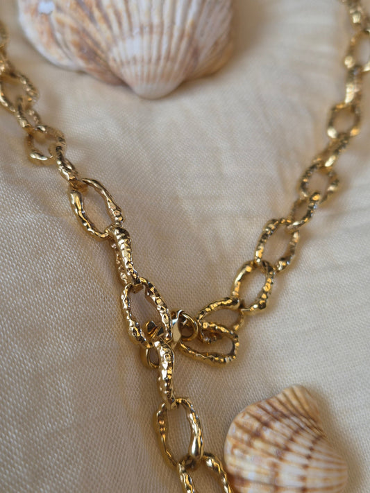 Closeup of gold plated necklace on a cream background with shells 