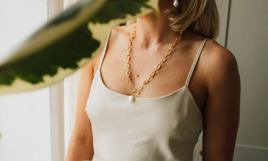 Female wearing pearl necklace with a white dress on a light background