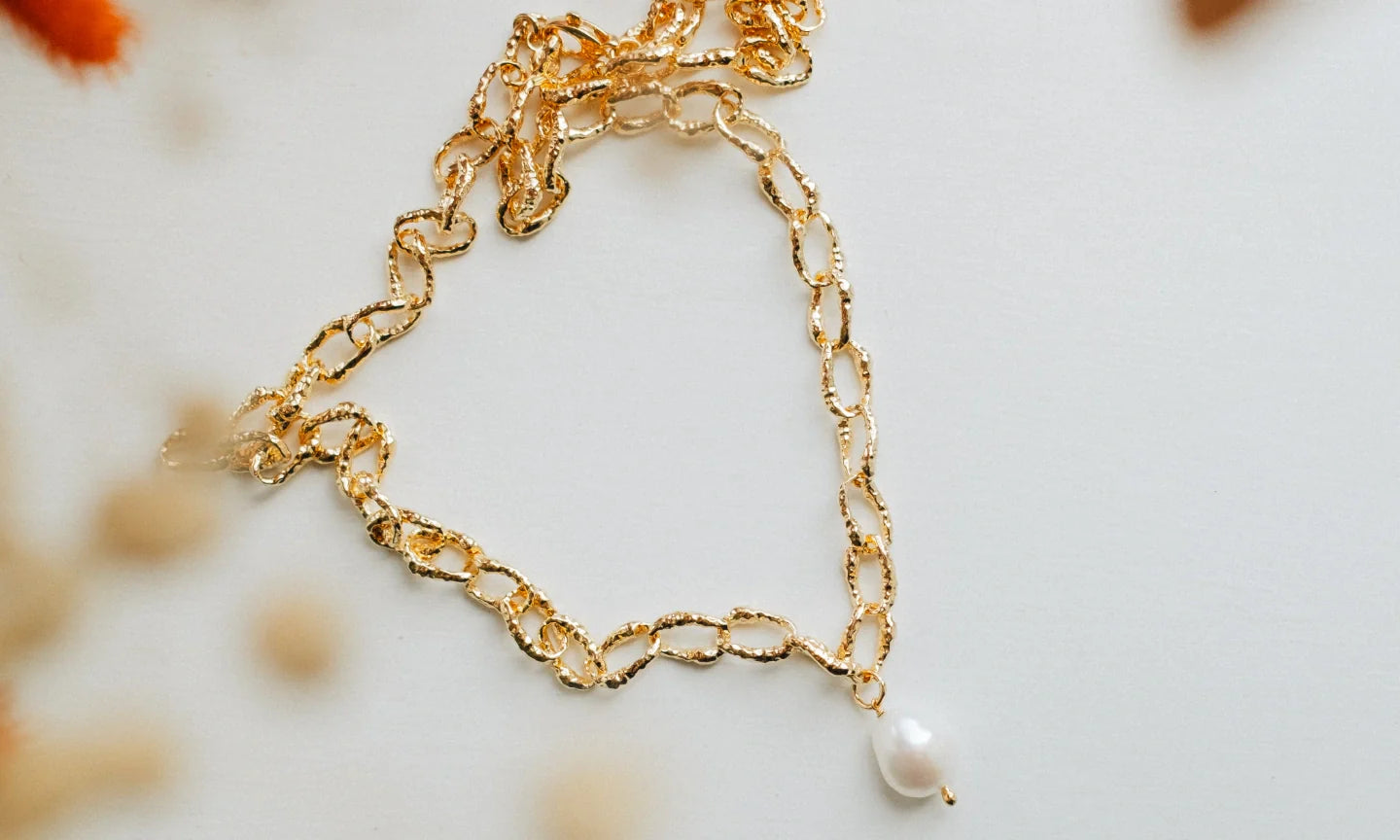 Flat lay of Shelly necklace on a white background with the gold shimmering